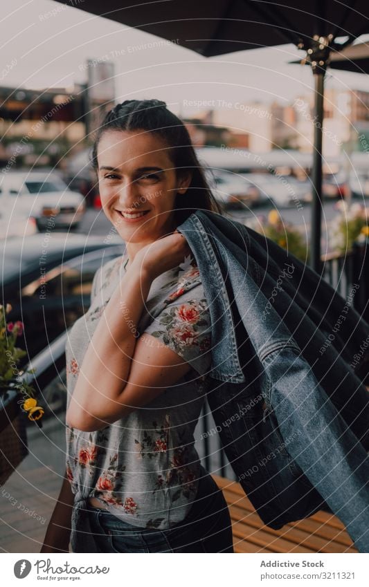 Lächelnde moderne Frau auf der Straße stehend hübsch lange Haare lässig trendy Sommer Jeansjacke Shorts Sonnenuntergang jung Erwachsener urban