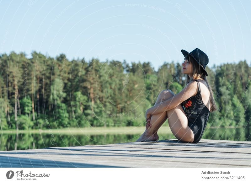 Junge Frau sitzt auf dem Pier in der Natur bewundernd See Freiheit reisen Tourismus ruhen Abenteuer Wald Tourist malerisch jung Glück Freude ländlich Ansicht