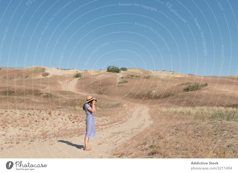 Junge Fotografin auf trockenem Feld Spaziergang Frau Straße Sand Landschaft Fotokamera Nachlauf ungepflastert trocknen staubig Gras sonnig Einsamkeit Sommer