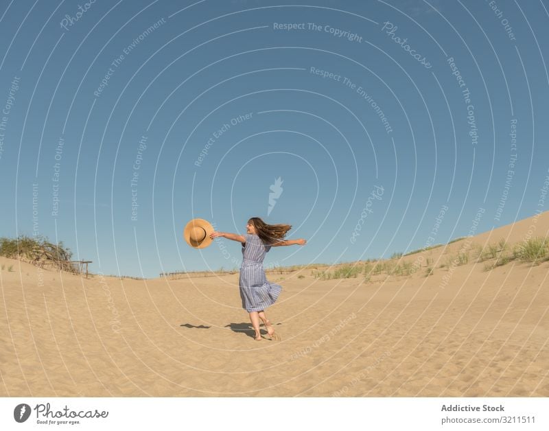 erwachsene Frau in Freizeitkleidung und Strohhut läuft und sich auf einer Sanddüne amüsiert Sommer verträumt Düne heiß Tourismus modern Klarer Himmel Kleid