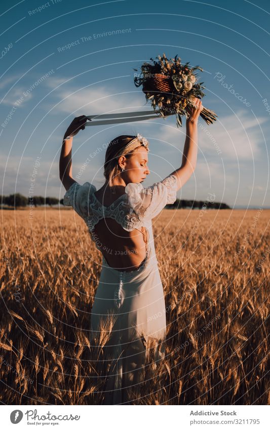 Charmante Frau im Kleid mit offenem Rücken, die die Hände mit einem Blumenstrauß hebt Braut Boho Spitze Totenkranz schön Stil Angebot sinnlich natürlich Sommer