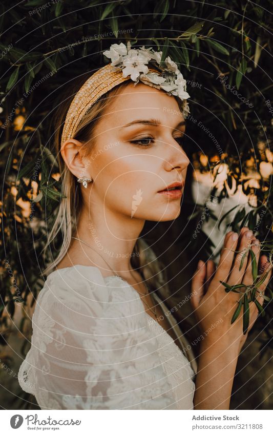 Charmante Frau in elegantem Kleid mit Blumen in Baumnähe Braut Boho Spitze Totenkranz träumen Stil Angebot sinnlich natürlich Sommer romantisch Hochzeit blond