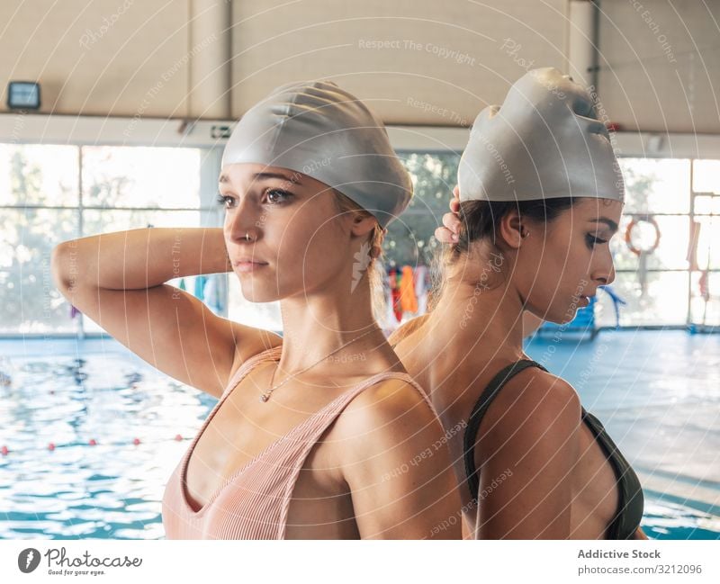 Schlanke Damen mit Badekappe im Schwimmbad Frauen Schwimmsport Pool Verschlussdeckel jung Team Wasser Fitnessstudio Freund Einrichtung Rücken an Rücken Schutz