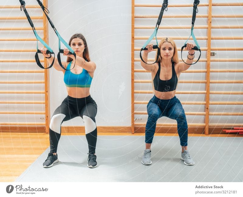 Starke Damen hocken mit Seilen Sportlerinnen Training Suspension Fitness Kniebeuge Athlet Übung trx Wohlbefinden Tatkraft Gerät Sportbekleidung Fitnessstudio