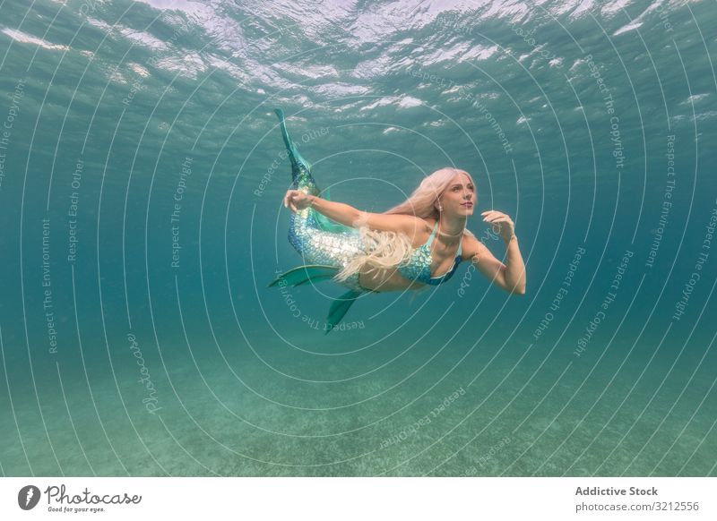 Blonde märchenhafte Meerjungfrau schwimmt unter Wasser schwimmen sorgenfrei Fischschwanz blau MEER tief blond schön Tageslicht Frau glänzend lange Haare hell