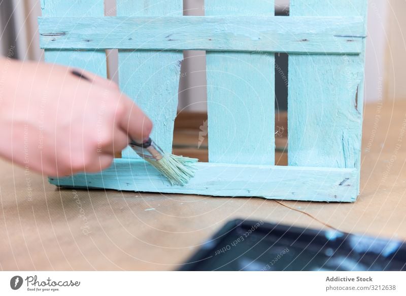 Frau malt Holzkiste in blauer Farbe mit Pinsel Anstreicher Bürste gemalt farbenfroh Design rustikal Kunst hölzern Handwerk Kasten dekorativ Künstler Stil