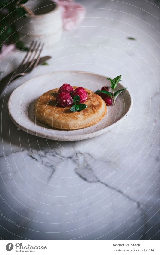 Pfannkuchen mit frischen Himbeeren auf Teller gold-braun Minze Murmel Tischplatte Frühstück geschmackvoll Blätter stylisch weiß Servieren Garnierung Dessert