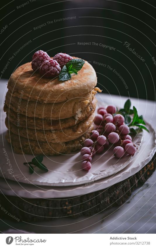 Stapel Himbeerpfannkuchen mit Honig auf dem Teller Pfannkuchen Himbeeren frisch Haufen gold-braun Liebling Murmel Porzellan Tischplatte Blumen Frühstück