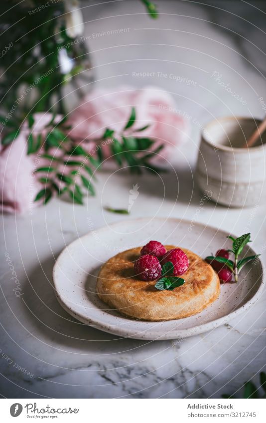 Pfannkuchen mit frischen Himbeeren auf Teller gold-braun Minze Murmel Tischplatte Frühstück geschmackvoll Blätter stylisch weiß Servieren Garnierung Dessert