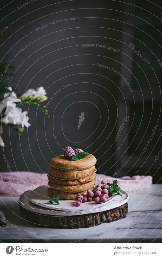 Stapel Himbeerpfannkuchen mit Honig auf dem Teller Pfannkuchen Himbeeren frisch Haufen gold-braun Liebling Murmel Porzellan Tischplatte Blumen Frühstück