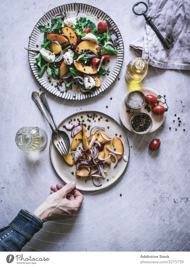 Salat mit Nektarinen und knusprigen Linsen Salatbeilage Pfirsich Zwiebel Tomate Kirsche Käse Hand Paprika Scheibe Erwachsener männlich Person Servieren Setzen