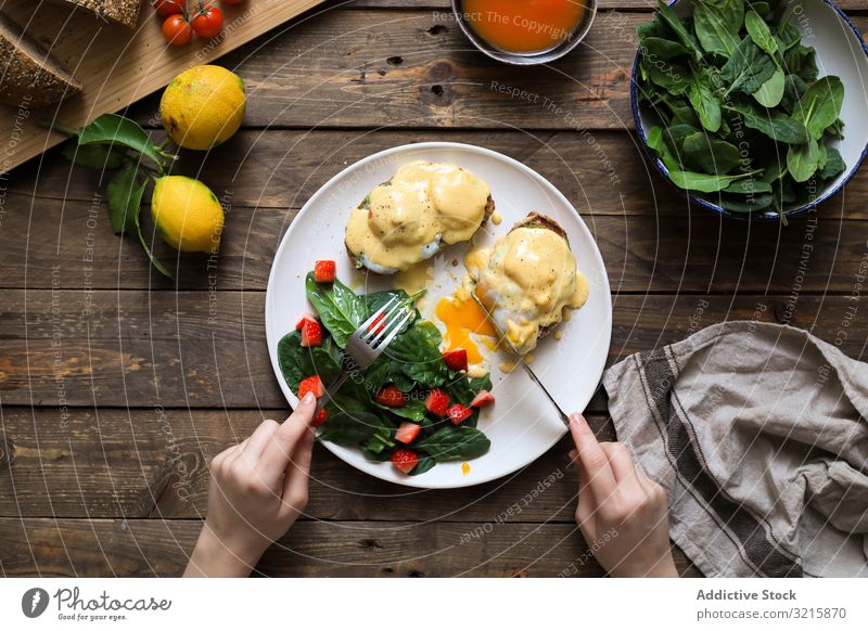 Person, die Rührei auf Brot mit grüner Soße und Tomate isst Ei Mahlzeit geschmackvoll verschlüsselt Lebensmittel Frühstück Teller lecker Tisch selbstgemacht