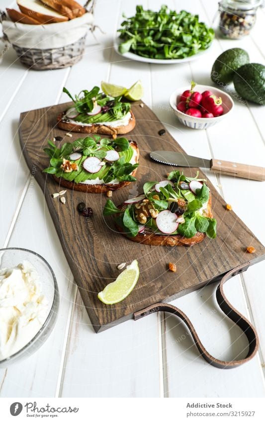 Vegetarische Sandwiches auf Schneidebrett Trinksprüche Gemüse Tisch Rettich Küchenkräuter Avocado Kalk Gesundheit Diät Veganer Vegetarier rustikal Snack