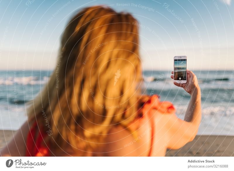 Frau in rotem Kleid fotografiert mit Smartphone Handy Fotografie Strand sandig Wasser Mitteilung Gerät Sommer benutzend Bild Freizeit Apparatur attraktiv