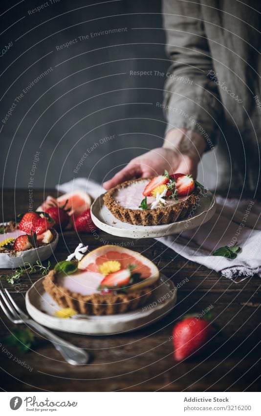 Chefkoch serviert einen Teller mit Erdbeer- und Zitruskuchen auf dem Tisch Erdbeeren Kuchen Zitrusfrüchte dienen Dessert rustikal Sommer Beeren