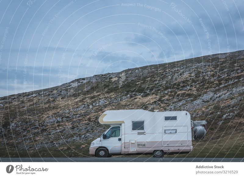 Wohnmobil in der Nähe des Hügels an bewölktem Tag reisen Landschaft Berghang wolkig Himmel Straße Wetter Fahrzeug geparkt Auto Verkehr Anhänger Wohnwagen