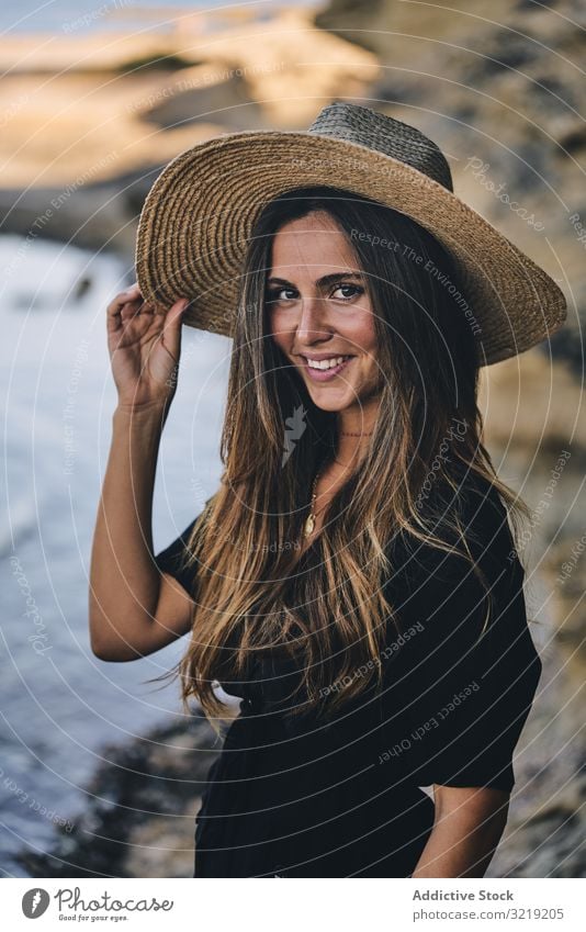 Fröhliche Frau hält Hut in der Luft Model heiter Strand Natur Lächeln stylisch jung attraktiv schön hübsch Sommer natürlich elegant posierend reisen Tourist