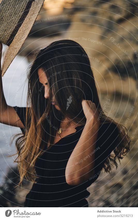 Fröhliche Frau hält Hut in der Luft Model heiter Strand Natur Lächeln stylisch jung attraktiv schön hübsch Sommer natürlich elegant posierend reisen Tourist