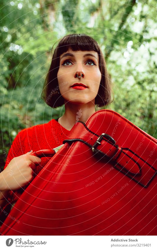 Frau in Rot mit großem roten Koffer im Wald reisen stylisch grün Gepäck Natur schön Tasche Piercing Warten Freiheit allein Ausflug Reise Baum Tourist elegant