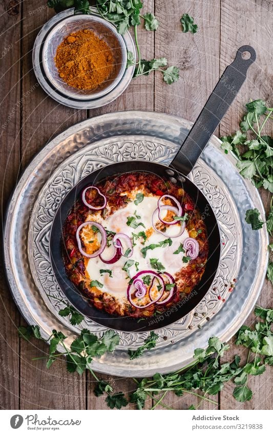 Duftende Shakshuka mit Zwiebelringen in der Pfanne Küche traditionell shakshuka Kurkuma Lebensmittel grün Mahlzeit Gemüse Schalen & Schüsseln Rezept Tisch