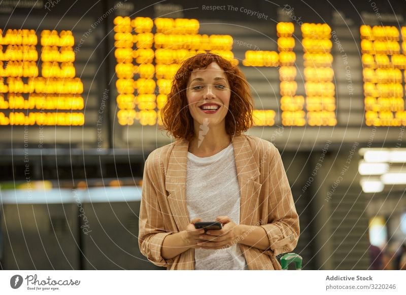 Rothaarige junge Frau benutzt Smartphone am Bahnhof Station reisen Business Urlaub Lächeln Tourist Eisenbahn Abheben Koffer Passagier Terminal Warten Zeitplan