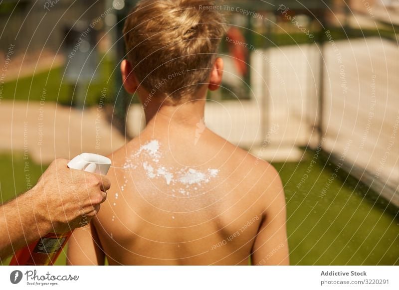 Gesichtsloser Mann trägt Sonnencreme auf Kind auf Vater Sahne Junge Zusammensein Sommer Strand Schutz Urlaub Pflege Hilfsbereitschaft Rücken Kindheit Familie