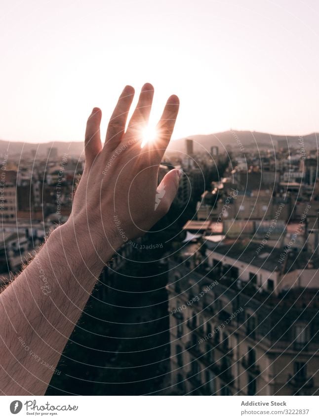 Person, die die Sonne mit der Hand auf dem Hintergrund der Altstadt verdunkelt Reisender Sonnenlicht Großstadt durch Sonnenstrahlen Tourismus Gebäude historisch