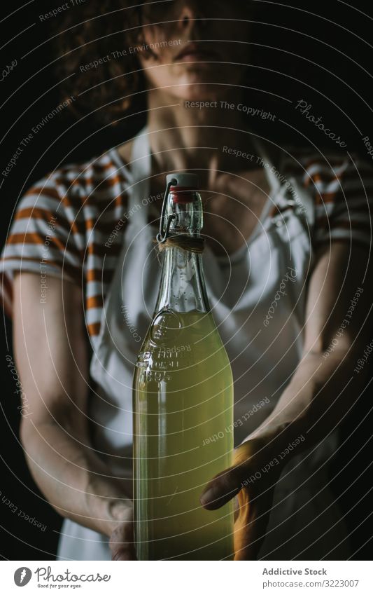 Weiblich mit Flasche Holunderblütensirup Frau Sirup Glas selbstgemacht Getränk trinken Erfrischung lässig ernst gestreift T-Shirt Schürze stehen Frucht