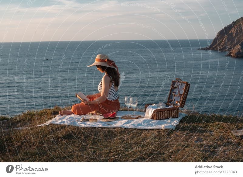 Frau liest auf Matte für Picknick am Meeresufer Buch Seeküste Strand Sommer lesen Freizeit Himmel MEER sich[Akk] entspannen Glas trinken Urlaub Sommerzeit