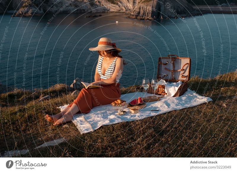 Frau liest auf Matte für Picknick am Meeresufer Buch Seeküste Strand Sommer lesen Freizeit Himmel MEER sich[Akk] entspannen Glas trinken Urlaub Sommerzeit