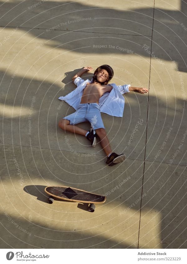 Junge am Boden im Skatepark Kind Mitfahrgelegenheit fallen Schutzhelm Sport Freizeit Hobby Verletzung jung anhaben Lügen Kindheit Sommer sonnig aktiv Stil