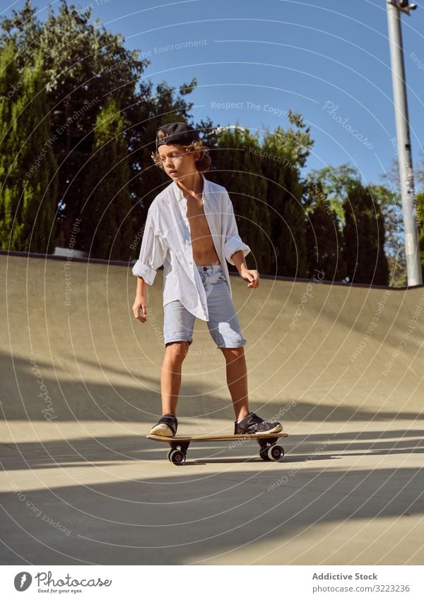 Kind mit Helm beim Skateboardfahren Skatepark Rampe Mitfahrgelegenheit Schutzhelm Sonnenlicht Sport Freizeit Hobby Junge jung anhaben Kindheit Sommer sonnig