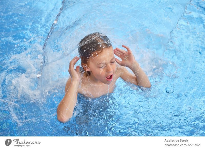 Junge im Schwimmbad mit blauem Wasser jung schwimmen Kind Schwimmer nach Luft schnappen geschlossene Augen offener Mund Wasserfall Wasserpark Aktivität Spaß