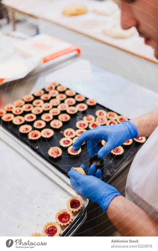 Anonymer Bäcker beim Dekorieren kleiner Kuchen Konditor Bäckerei Gebäck Arbeit Qualität Lebensmittel traditionell Mann Vorbereitung Inszenierung