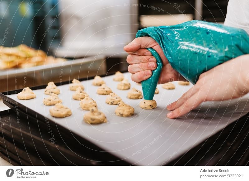 Erntebäcker, der Teig auf einem Blech auspresst Konditor Bäckerei Teigwaren drücken Tablett Keks Arbeit Küche Vorbereitung professionell Lebensmittel Papier