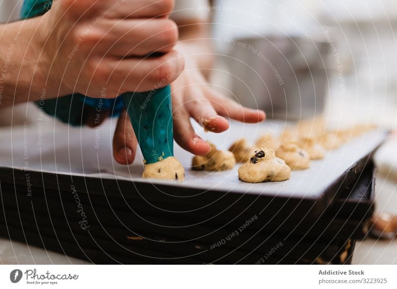 Erntebäcker, der Teig auf einem Blech auspresst Konditor Bäckerei Teigwaren drücken Tablett Keks Arbeit Küche Vorbereitung professionell Lebensmittel Papier