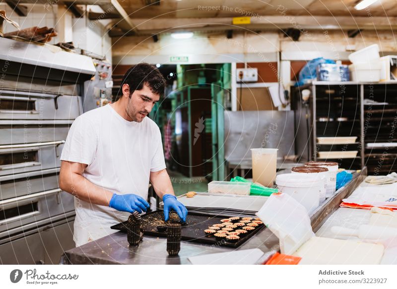 Erntebäcker, der Teig auf einem Blech auspresst Konditor Bäckerei Teigwaren drücken Tablett Keks Arbeit Küche Vorbereitung professionell Lebensmittel Papier