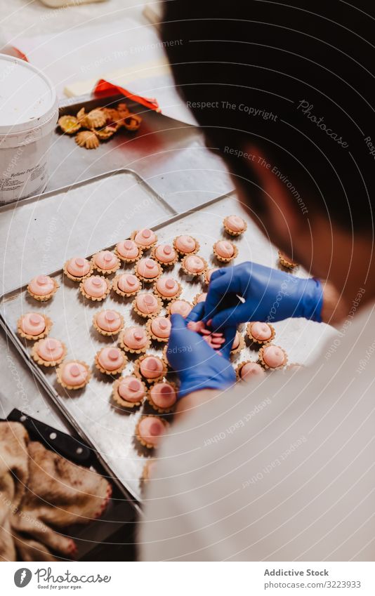 Anonymer Bäcker beim Dekorieren kleiner Kuchen Konditor Bäckerei Gebäck Arbeit Qualität Lebensmittel traditionell Mann Vorbereitung Inszenierung