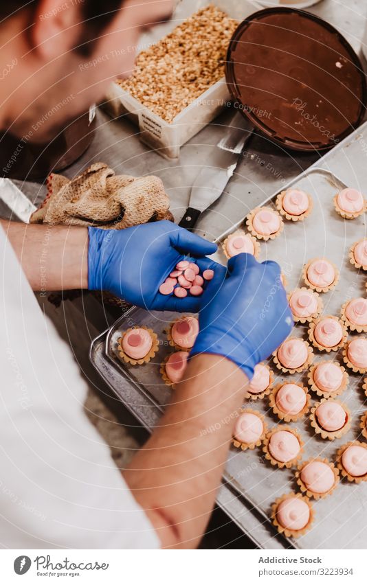 Anonymer Bäcker beim Dekorieren kleiner Kuchen Konditor Bäckerei Gebäck Arbeit Qualität Lebensmittel traditionell Mann Vorbereitung Inszenierung