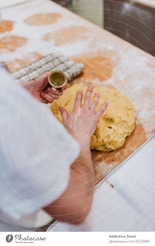 Bärtiger Konditor legt Teig in Tasse Bäckerei Teigwaren setzen Tisch Küche Gebäck Vorbereitung frisch Mann roh professionell Lebensmittel Küchenchef Restaurant