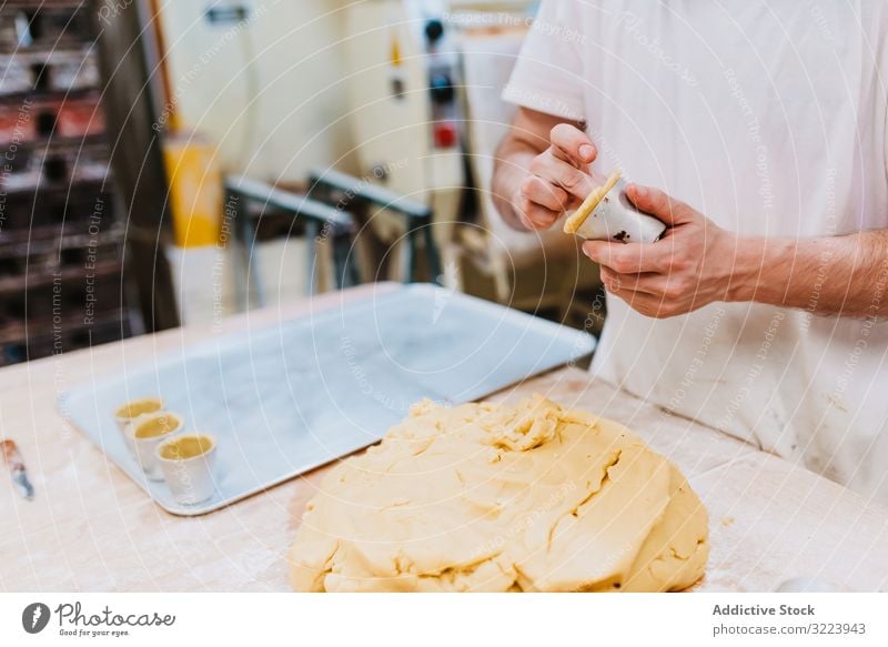 Bärtiger Konditor legt Teig in Tasse Bäckerei Teigwaren setzen Tisch Küche Gebäck Vorbereitung frisch Mann roh professionell Lebensmittel Küchenchef Restaurant