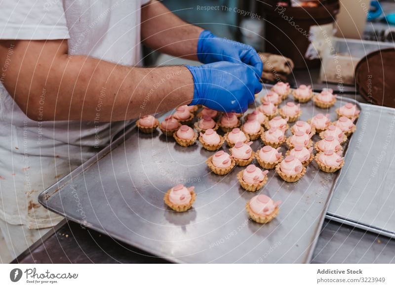 Anonymer Bäcker beim Dekorieren kleiner Kuchen Konditor Bäckerei Gebäck Arbeit Qualität Lebensmittel traditionell Mann Vorbereitung Inszenierung