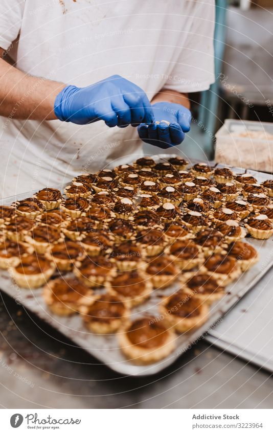 Getreidekoch, der Gebäck mit Nüssen dekoriert Konditor Bäckerei Nut Dekor Arbeit Kuchen Qualität Lebensmittel traditionell Mann Vorbereitung Inszenierung