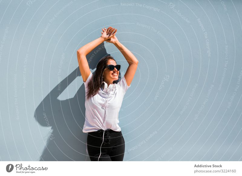 Fröhliche, ungezwungene Frau mit Sonnenbrille steht auf Stadtstraße Kopfhörer stylisch heiter trendy tausendjährig schön Apparatur Musik Gerät stehen Generation