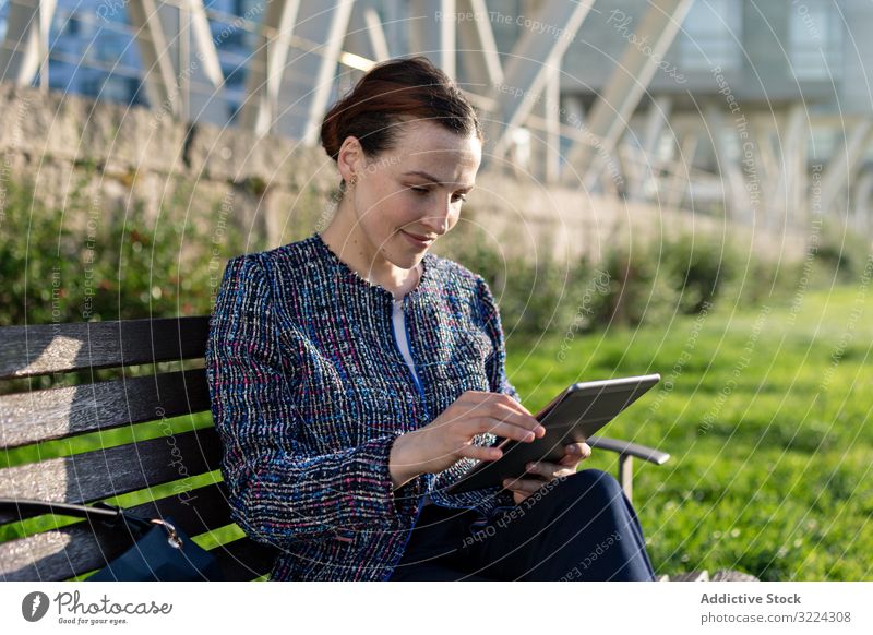 Geschäftsfrau blättert im Park Tablette benutzend ernst Stirnrunzeln Bank sitzen sonnig tagsüber Frau Großstadt urban Arbeit Job Internet Gerät Apparatur