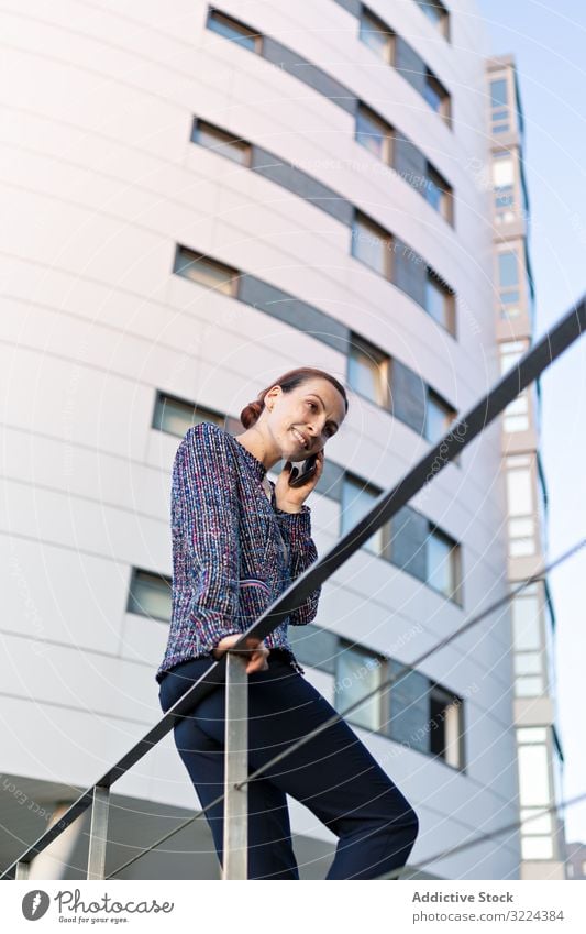 Lächelnde Geschäftsfrau nimmt Telefonanruf entgegen Smartphone Straße reden Gebäude modern Großstadt urban Frau Mitteilung Arbeit Job Mobile Gerät Apparatur