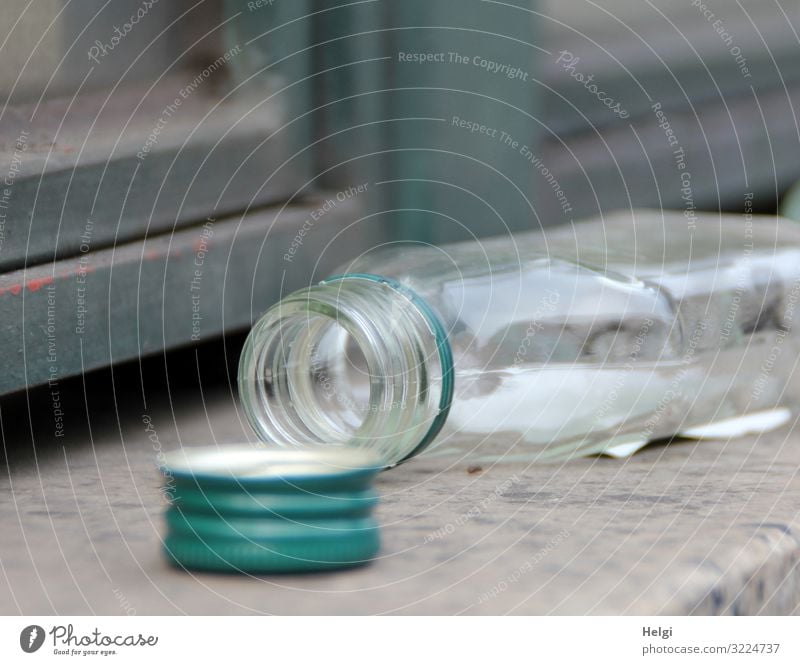 leere geöffnete Alkoholflasche liegt auf einer Mauer Wand Flasche Verschluss Verschlussdeckel liegen authentisch klein grau grün Gefühle Verzweiflung