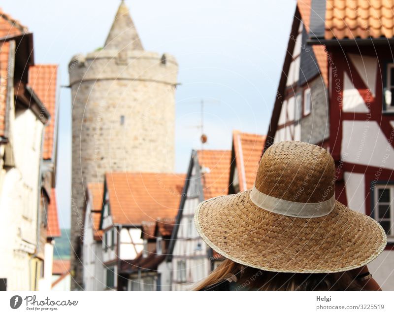 Dame mit Sonnenhut spaziert in einer Altstadt mit Fachwerkhäusern und historischem Turm Mensch Erwachsene 1 Alsfeld Stadt Haus Bauwerk Architektur Fachwerkhaus