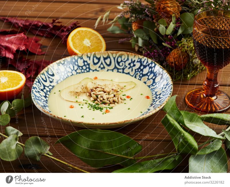 Zitrusfrüchte und Weincremesuppe inmitten von Blumenzweigen Suppe Sahne Zweig Pflanze Tisch Feinschmecker Vichyssoise Porree Küche appetitlich Feinkostladen