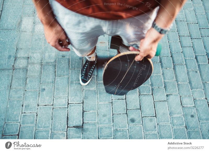 Sportlicher Mann trägt Longboard, während er auf der Straße steht modern urban führen Großstadt stehen Halt sportlich jung Erwachsener passen stark extrem Arme